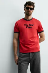 Camiseta de corte regular color rojo con cuello redondo y bordes de mangas en color azul marino. Presenta una estampa frontal con la frase 'The Best Plan.' en color azul marino.
