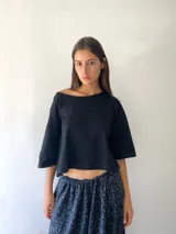 Remera básica de color negro, con cuello redondo amplio y mangas cortas de corte holgado.
