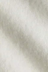 Cárdigan de punto fino, color blanco, de manga larga y corte corto (cropped). Presenta escote redondo y cierre frontal con botones nacarados.