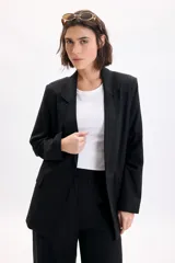 Blazer sastrero de lino color negro, con solapas clásicas, bolsillos delanteros con solapa y diseño de corte recto.