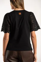 Remera de algodón peinado color negro, con mangas cortas de broderie con diseño calado y terminación festoneada. Presenta un corte oversize y cuello redondo.