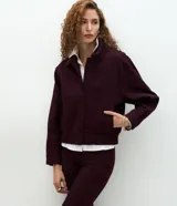 Campera bomber de sarga acanalada en color bordó, con cuello camisero, cierre frontal con botones forrados y puños con ajuste elástico.