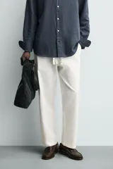 Pantalón de corte relajado confeccionado en una mezcla de algodón y lino. Presenta cintura elástica con cordón ajustable, bolsillos laterales y bolsillos traseros de vivo.