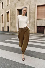 Pantalón de tiro medio con diseño bombacho, frunces delanteros y pierna abullonada con puños ajustados. Incluye bolsillos frontales y un cinturón decorativo con cadena metálica.