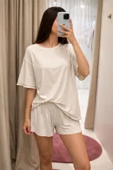 Conjunto de pijama compuesto por un remerón de corte amplio y un short a juego. Presenta un diseño en color beige con detalles de ribetes en color marrón en los bordes. Confeccionado en una mezcla de viscosa, lino y elastano, ofreciendo una caída suave y liviana.