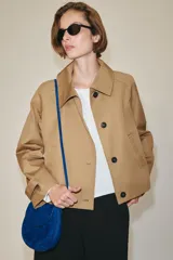 Chaqueta corta de cuello subido y manga larga con trabilla y botón. Cuenta con bolsillos de vivo en el delantero y cierre frontal con botones.
