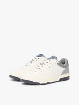 Zapatillas de baloncesto Tommy Hilfiger de corte bajo, color blanco con detalles en gris, azul y suela bitonal. Presentan exterior de piel con paneles de ante y mezcla de texturas, cordones blancos y detalles distintivos de la marca.