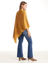 Poncho tejido de punto con diseño asimétrico y aberturas laterales para los brazos.
