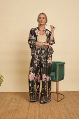 Conjunto de dos piezas compuesto por una campera bomber y un pantalón ancho, ambos confeccionados en satén negro con estampado floral y de aves. La campera cuenta con cierre frontal y puños elastizados, mientras que el pantalón tiene tiro alto y cintura elástica con cordón ajustable.