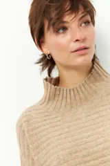 Polera gris de tejido tramado, cuello alto y mangas holgadas.