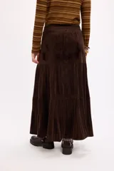 Falda larga de color negro con textura símil terciopelo, presenta un diseño con volados y detalle de tachas en la cintura.