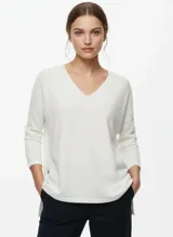 Sweater de punto color blanco, con escote en V y calce holgado, de manga larga.