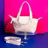 Cartera de cuero vacuno color blanco con textura tipo cocodrilo. Tiene doble asa corta, correa larga ajustable y removible, bolsillo trasero con cierre, forro interior de tela con bolsillo con cierre y bolsillo para celular.