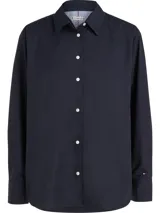 Camisa azul marino de algodón orgánico con corte amplio, cuello inglés, cierre frontal con botones blancos y logo de Tommy Hilfiger bordado en la manga.