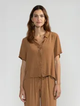 Camisa marrón de manga corta en crepé de viscosa suave, con cuello camisero y detalle floral en la botonadura central.