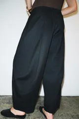 Pantalón de tiro medio con corte wide leg y cintura elástica ajustable. Presenta bolsillos laterales ocultos en las costuras y un diseño de pierna ancha con caída fluida.