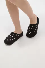 Suecos tipo zueco color negro con acabado de gamuza, decorados con tachas metálicas plateadas circulares. Poseen suela plana y diseño abierto en el talón.