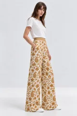 Pantalón de algodón de tiro alto con diseño amplio, bolsillos laterales y estampado tipo paisley y floral en tonos mostaza sobre fondo blanco.