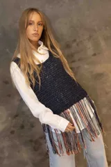 Musculosa tejida en punto calado color negro con destellos brillantes, presenta un diseño de flecos largos en el ruedo que combinan tonos rojizos, dorados y oscuros.