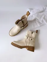 Botas cortas color crudo de cuero, con cierre lateral, pulsera desmontable y suela marrón.