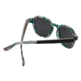 Lentes de sol Indie con montura redonda de acetato con estampado botánico en tonos verdes y grises.