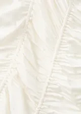 Vestido corto satinado de color beige, con diseño entallado, fruncidos ajustables laterales, escote de pico y tirantes finos.