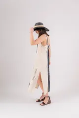 Vestido largo de lino con diseño bicolor en beige y crudo, escote en V y breteles regulables. Presenta detalles de bordados geométricos en el frente y tajos laterales.