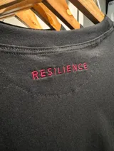 Remera unisex de corte oversize, color negro, confeccionada en algodón. Presenta un bordado frontal con la palabra 'GAINS.' en color rojo.