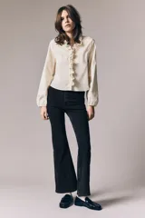 Jean de denim elástico color negro, de tiro alto, con cierre de botón y piernas acampanadas. Cuenta con bolsillos decorativos delanteros y bolsillos traseros.