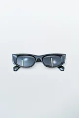 Lentes de sol negros con montura rectangular y bordes anchos, estilo futurista.