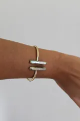Pulsera dorada rígida con apliques de nácar.