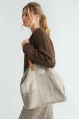 Bolso tipo shopper de lana fina sin teñir, con diseño de parches en tonos beige y gris. Cuenta con asas de cuero, cierre superior y etiqueta de cuero con logo de la marca.