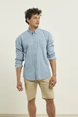 Camisa de hombre de denim azul, manga larga, con cuello buttondown y un bolsillo de parche en el pecho izquierdo.