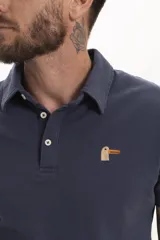 Remera tipo polo azul marino de manga corta con cuello clásico y cierre de dos botones. Presenta un pequeño bordado de un pájaro en el pecho.