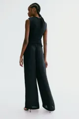Pantalón holgado de satén negro, con piernas amplias, cintura elástica con cordón ajustable y bolsillos laterales.