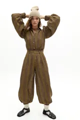 Camisa de lino con estampado de rayas verticales en tonos tierra. Presenta cuello camisero clásico, cierre frontal con botones de nácar, mangas largas abullonadas y puños con terminación ondulada.