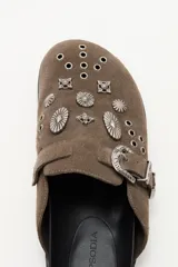 Zueco de cuero descarne negro con diseño de estilo western, decorado con tachas metálicas plateadas y una hebilla lateral ajustable.