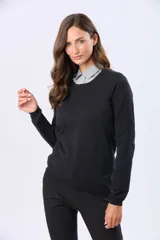 Buzo tejido en hilo de algodón color beige, con cuello redondo y manga larga. Presenta un corte clásico y un pequeño detalle metálico en la parte inferior izquierda.