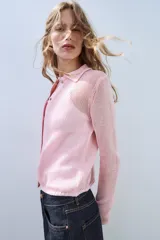 Chaqueta de punto color rosado con cuello polo, manga larga y cierre frontal con botones.