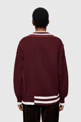 Sweater de punto color borgoña con cuello en V, diseño asimétrico con rayas en contraste y detalle de tejido texturizado en un lateral.