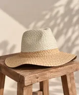 Sombrero de playa bicolor con diseño tejido, copa tipo fedora y ala ancha. Combina tonos beige y tostado.