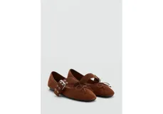 Zapatos planos de gamuza marrón, con punta fina, cierre de dos tiras con hebillas metálicas en el empeine y detalle de lazo pequeño en la puntera.