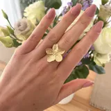 Anillo dorado con forma de flor de cinco pétalos con textura acanalada.