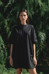 Camisa blanca de corte oversize y largo midi, confeccionada en algodón. Presenta cuello mao, cierre frontal oculto por tapeta y mangas cortas con dobladillo. Incluye un pequeño bordado de una flor en el pecho.