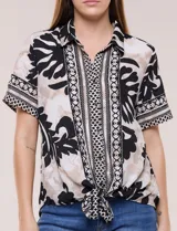 Camisa de gasa de manga corta con estampado en blanco, negro y beige, cuello con solapa, cierre frontal de botones y diseño con nudo en el ruedo.