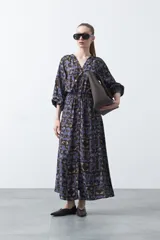 Vestido largo de silueta fluida con estampado abstracto en tonos azul, marrón y beige. Presenta escote en V con botones forrados y cintura elastizada. Mangas 3/4 abullonadas.