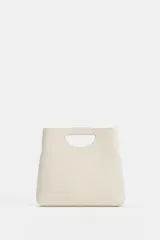 Bolso de mano de piel en color crudo, con cuerpo asimétrico, asa de mano integrada con aperturas laterales y correa bandolera extraíble. Cuenta con un bolsillo interior.