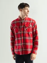 Camisa de franela a cuadros color celeste, gris y negro, de manga larga con dos bolsillos frontales con solapa abotonada.