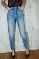 Jeans de tiro alto con corte mom fit, diseño de cinco bolsillos y detalle de raya planchada frontal. Cierre frontal con cremallera y botón.