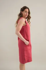 Vestido midi de lino color beige, de silueta relajada, escote redondo, sisas amplias y bolsillos delanteros aplicados.